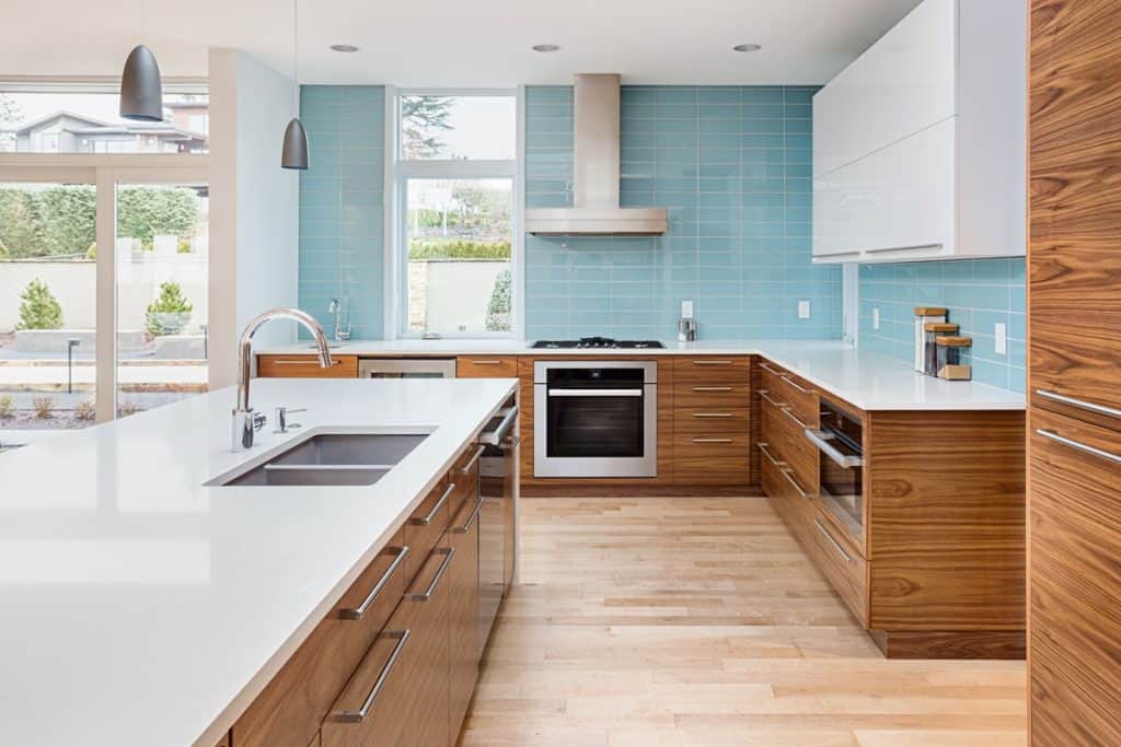 Kitchen interior with blue backsplash, white countertop and oak cabinets
