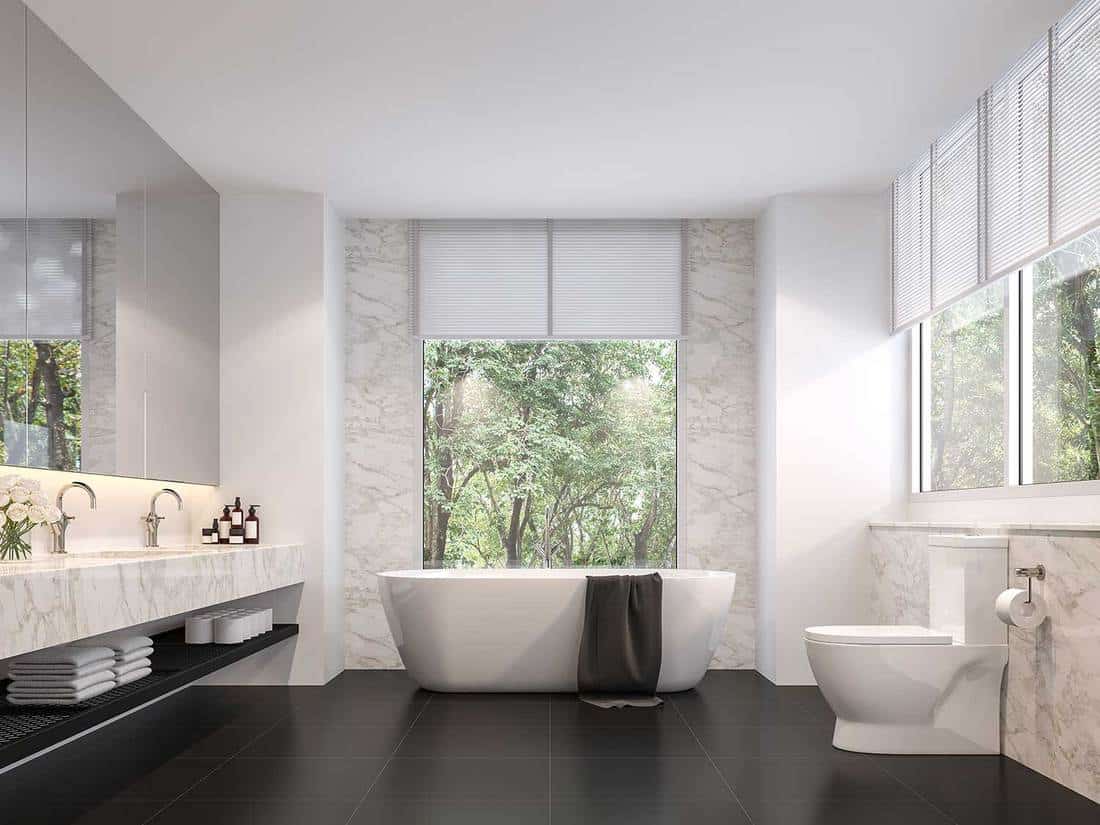Luxurious bathroom with natural views, black tile floors, white marble walls and large windows sunlight shining into the room