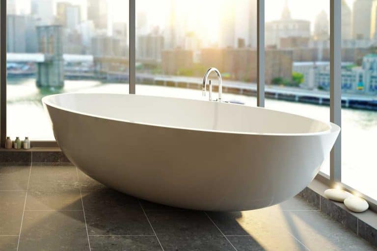 Modern bathroom with city skyline view large glass windows, How Much Does An Acrylic Bathtub Weigh?