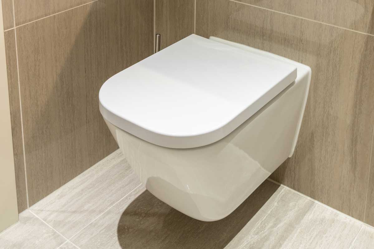 Modern toilet in clean apartment with tiled walls and floor, What Is The Standard Toilet Room Size And How Big Is A Typical Toilet?
