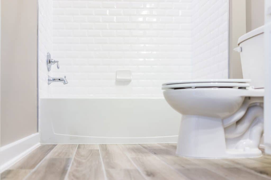 Salle de bain moderne et blanche avec des carreaux de douche et des planchers de bois franc à partir du rez-de-chaussée