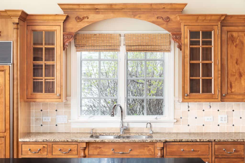 Oak cabinets and a beautiful arched aesthetic with backsplash surrounding the white window