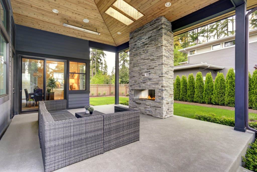 Outdoor porch with wicker chairs, black exterior siding and wooden ceiling