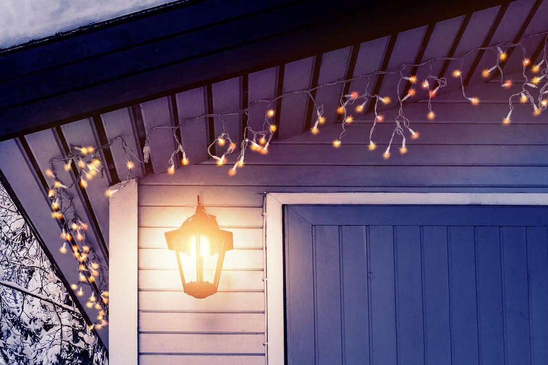Porch of the house is decorated in the traditional Scandinavian style with a lantern and Christmas lights , How Can I Light My Porch Without Electricity? [A Complete Guide]