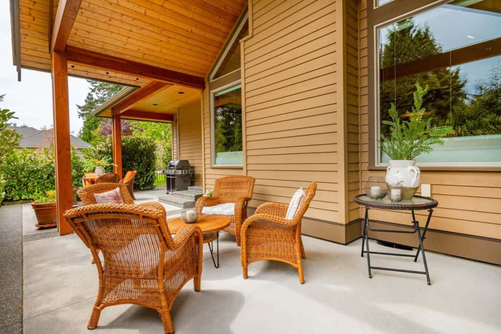 Rattan chairs outside a modern wooden porch ceiling of a modern house