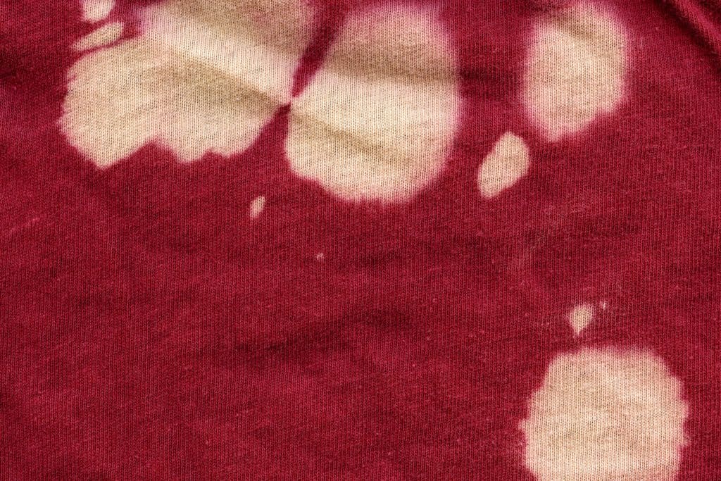 Red fabric with bleach stains