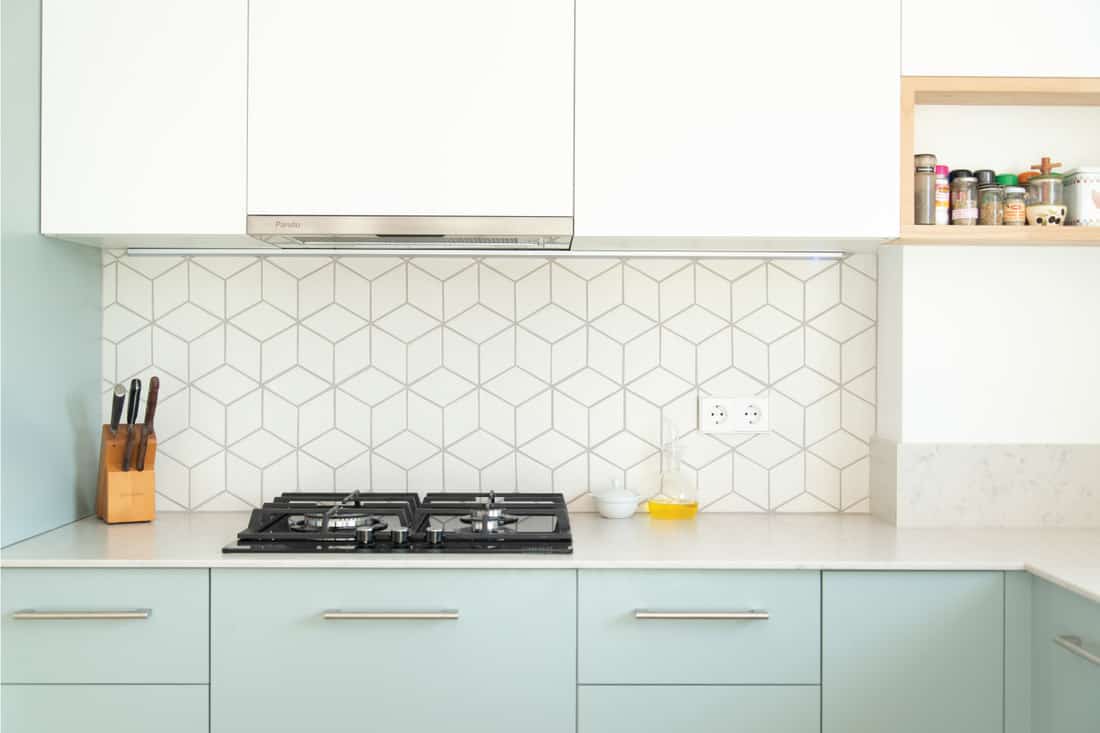 Scandinavian style kitchen with geometric backsplash and blue and white cupboards