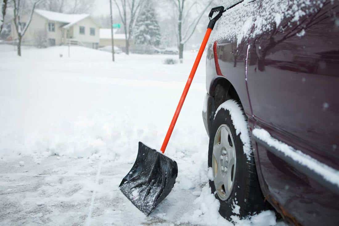 Shovel on driveway during winter snow, When To Salt The Driveway - Before Or After Snow?