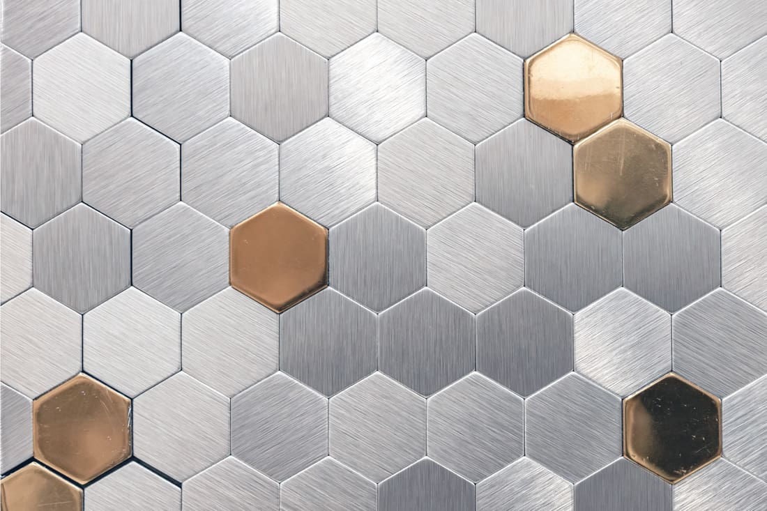 Silver metal mosaic tile with golden elements. Metal mosaic in the form of honeycombs.