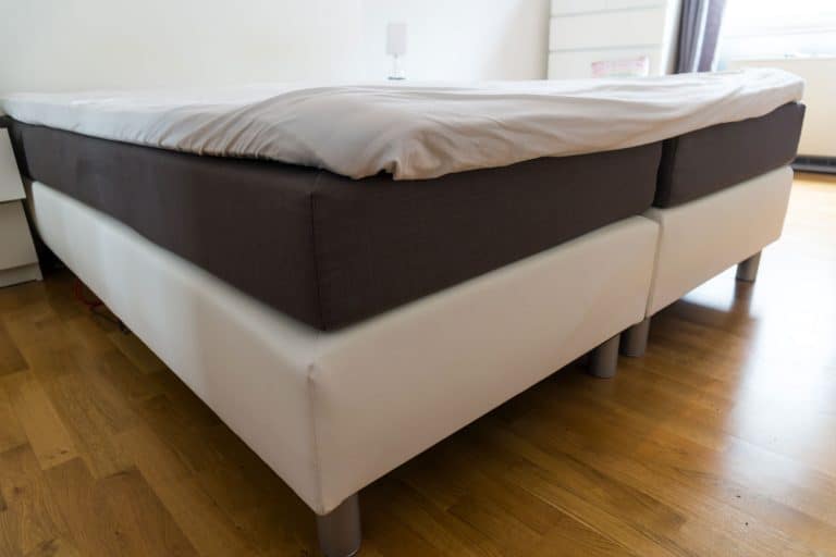 Two box springs bed laid out on a wooden flooring inside a spacious living room, Can You Leave A Box Spring On The Floor?