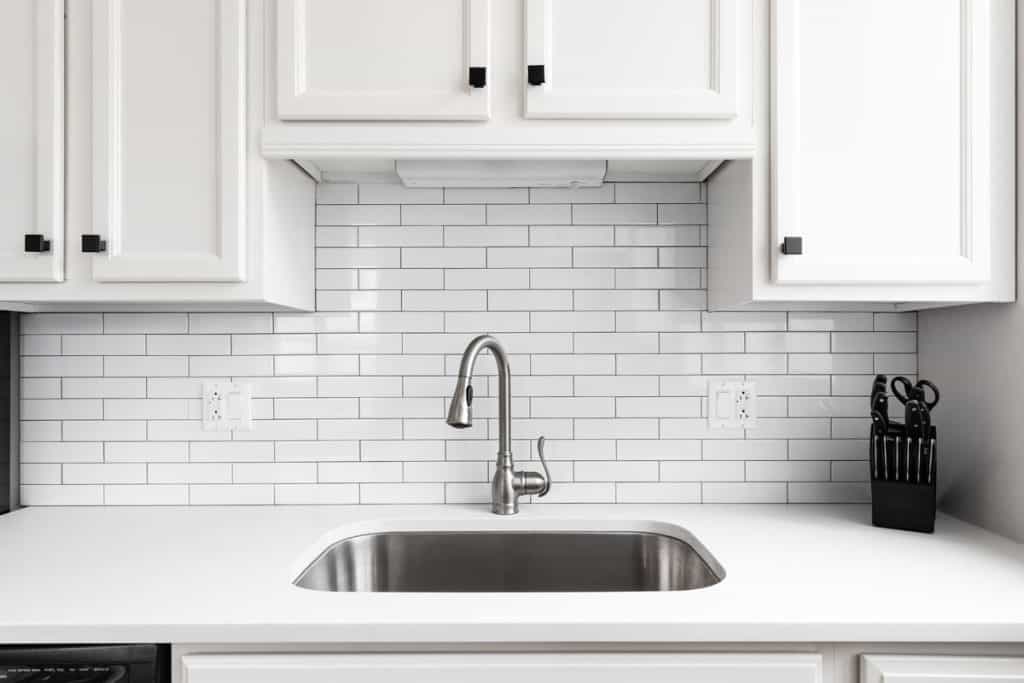 White kitchen cabinets and a matching stainless steel faucet and sink