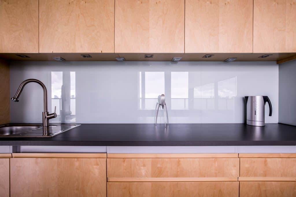 Wooden kitchen unit in stylish contemporary interior and white backsplash