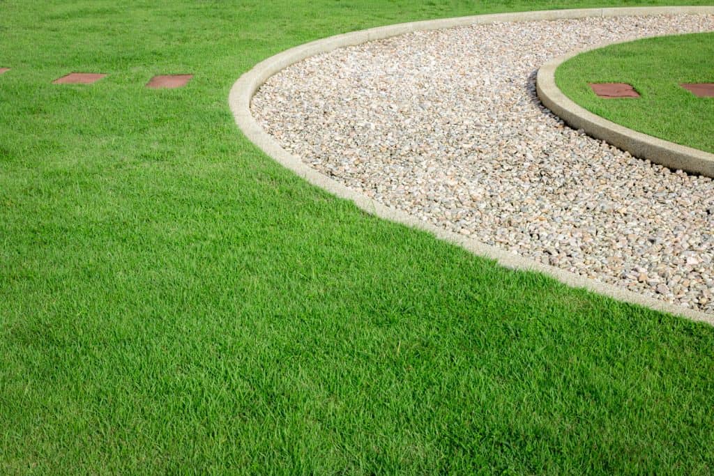 field green grass with stone path and way of white stone in the garden