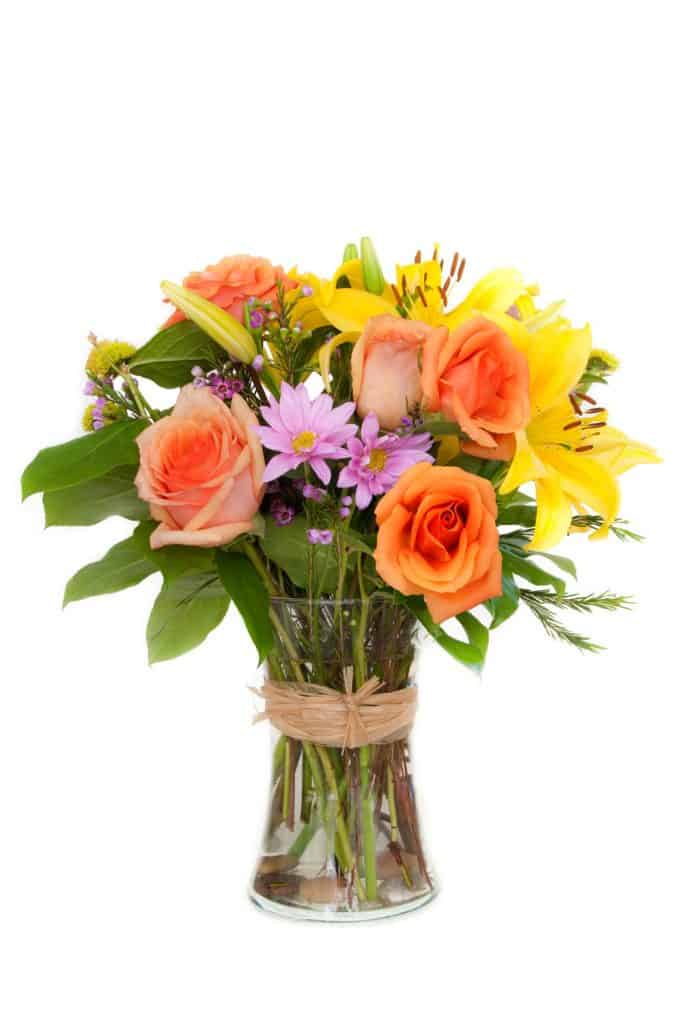 A beautiful arrangement of roses, lilies, and leaves making a gorgeous bouquet