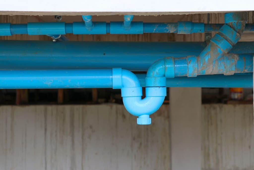 A blue PVC trap with a series of waster lines in a commercial building