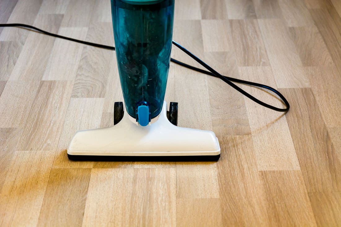 A blue cased vacuum cleaner vacuuming the wooden floor, How Long Do Bissell Vacuums Last?