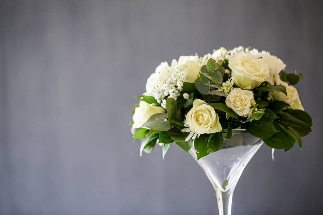 A bouquet of white roses in a large martini glass