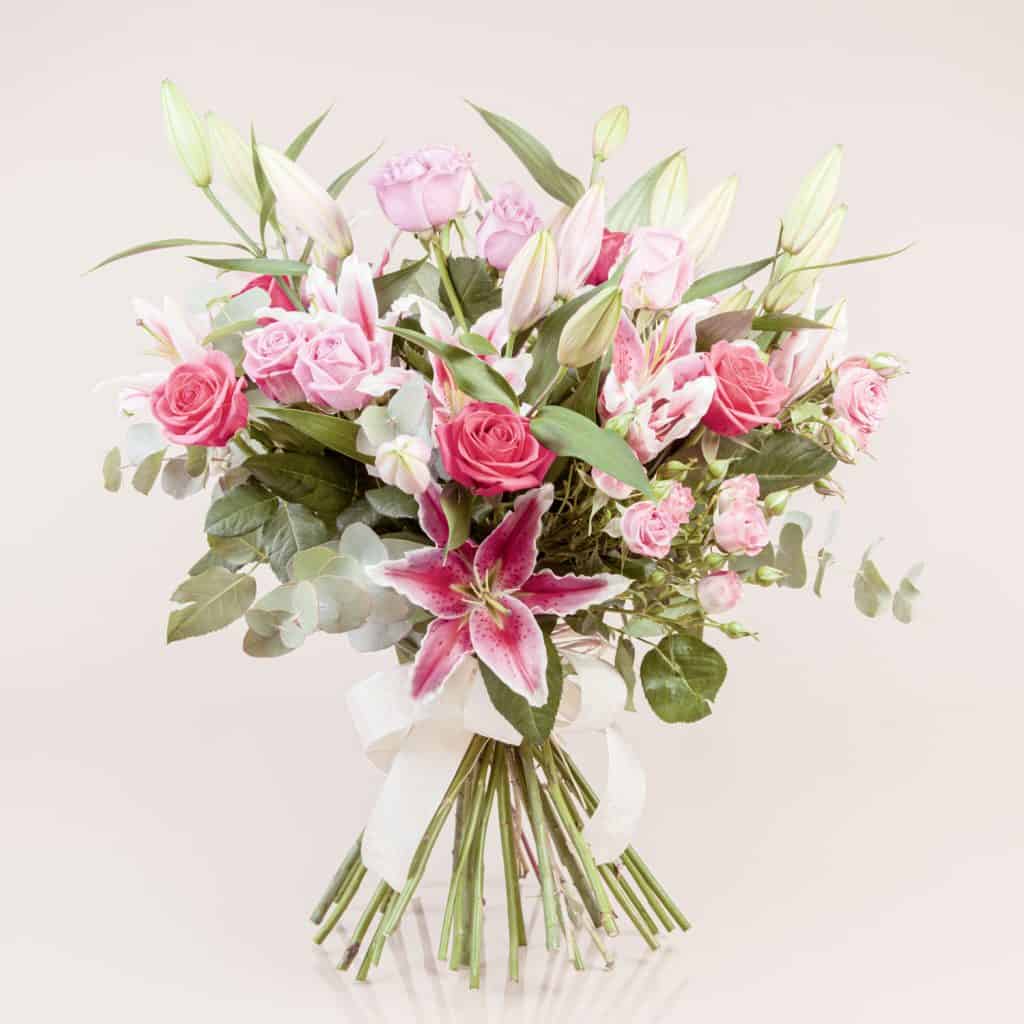 A gorgeously arranged flower vase using pink lilies and red roses