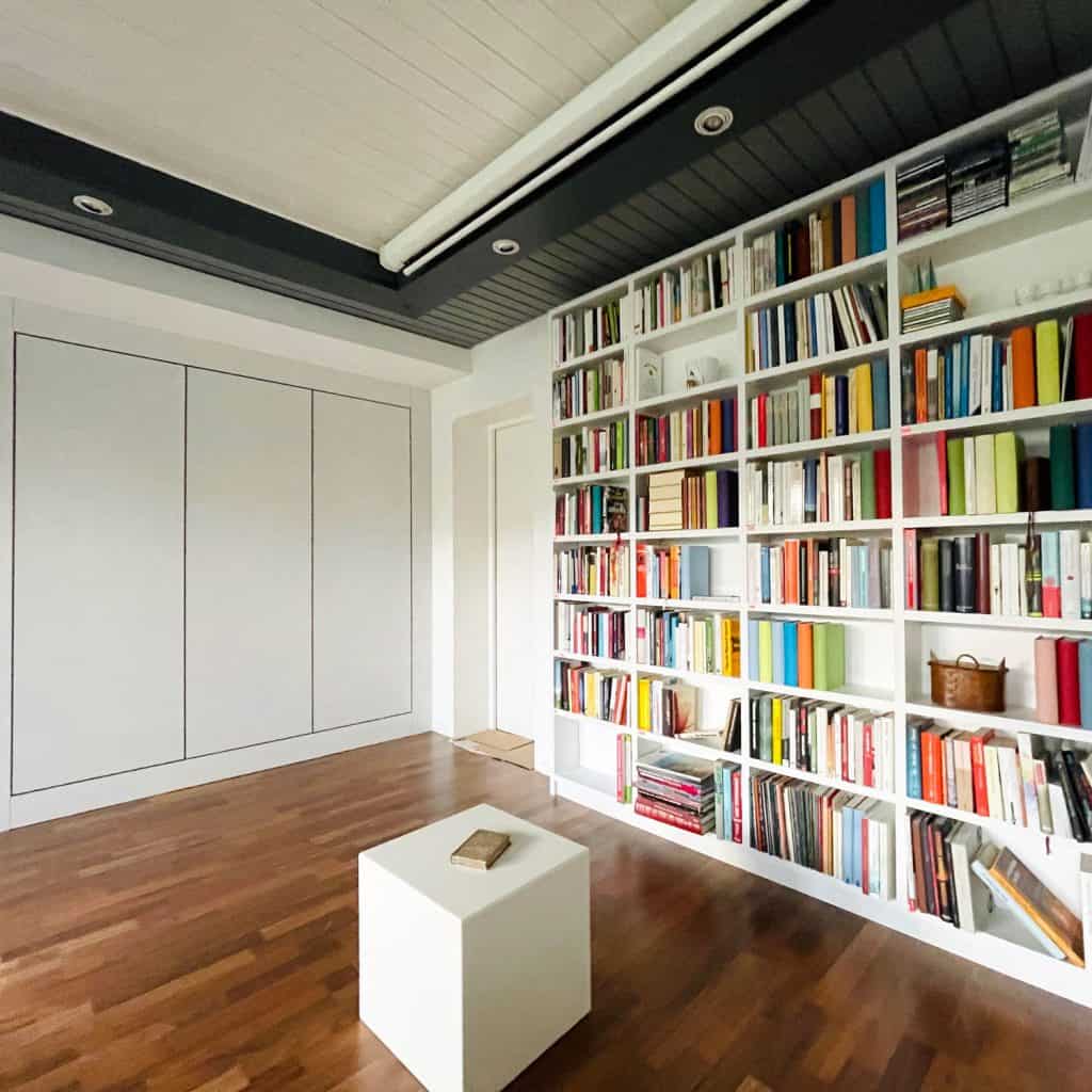 A large library with books filed in a tall white colored bookshelf