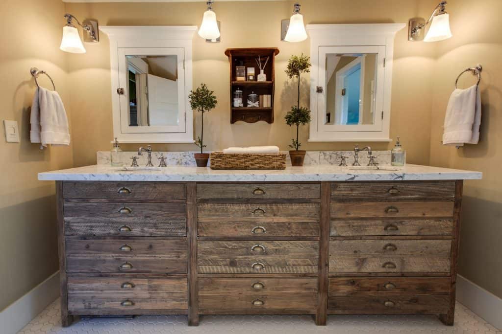 A rustic cabinetry with a granite countertop and two small square mirror