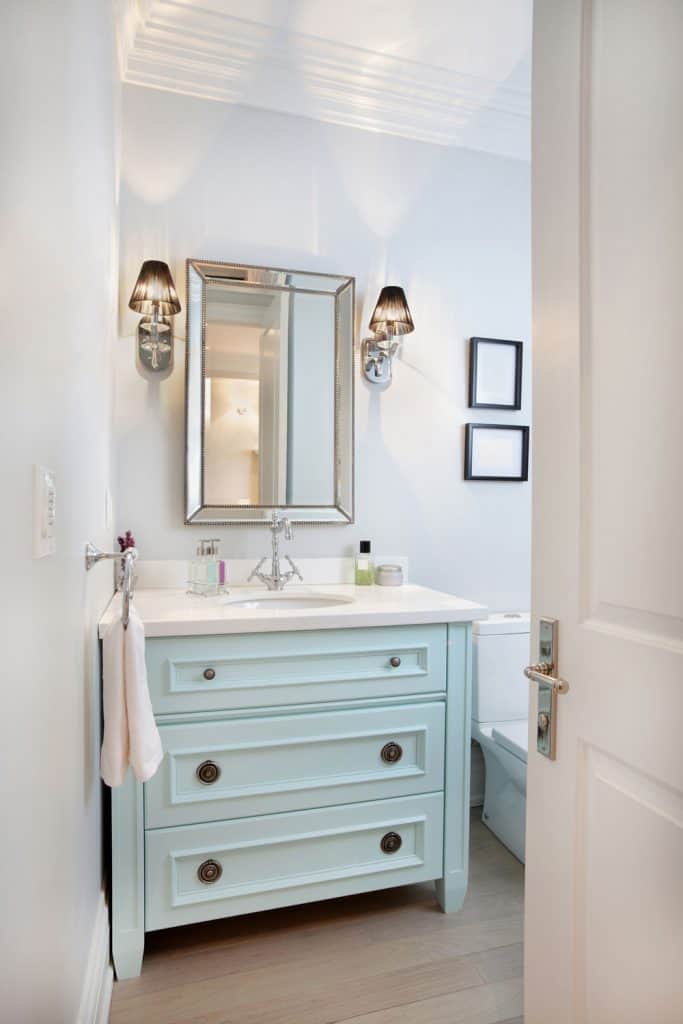 A small light blue painted drawer cabinet below the vanity