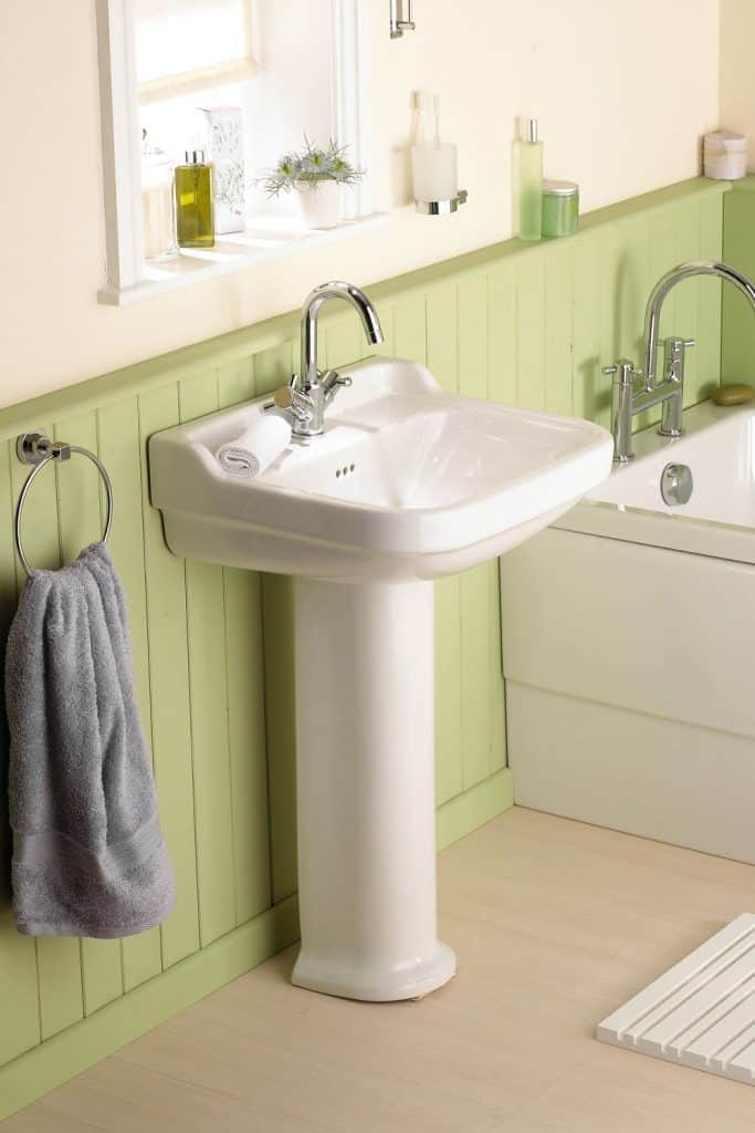 A small sink inside a green toned bathroom