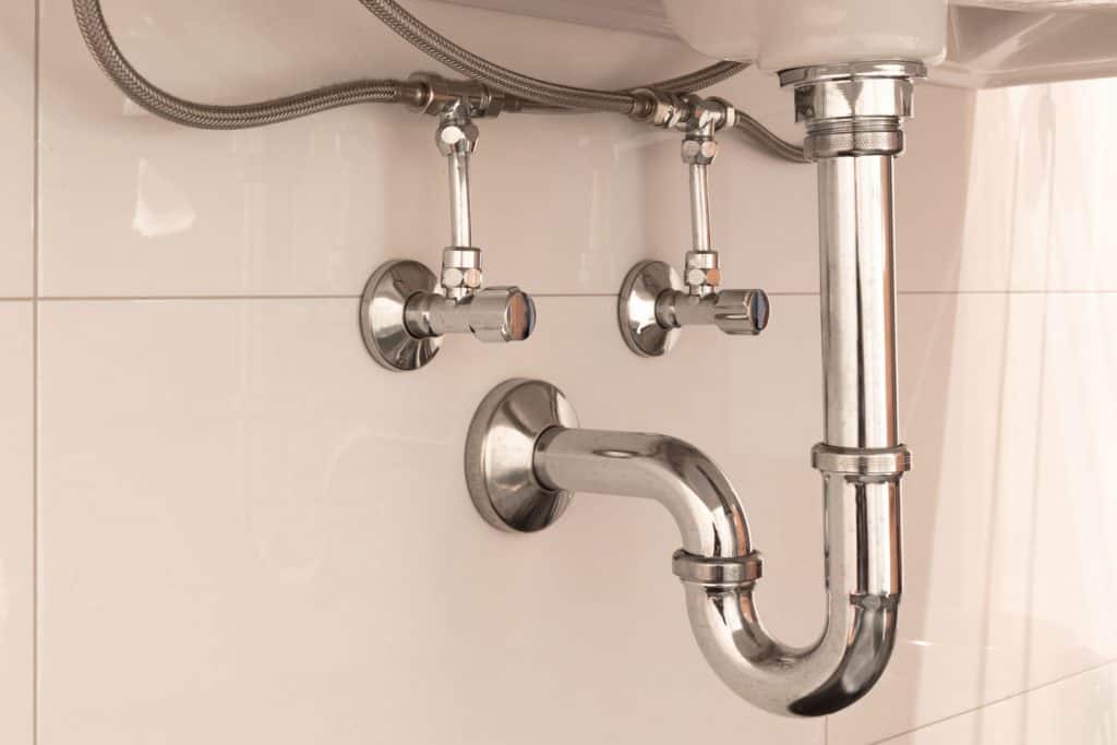 A stainless steel plumbing line of a sink inside a modern bathroom