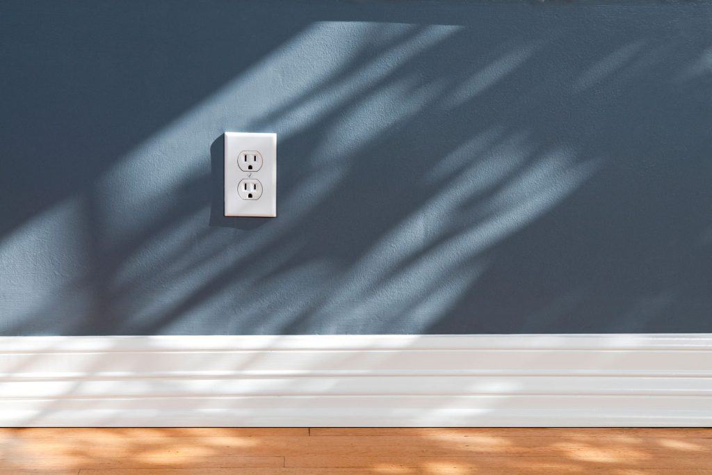 A two outlet on a dark blue colored wall