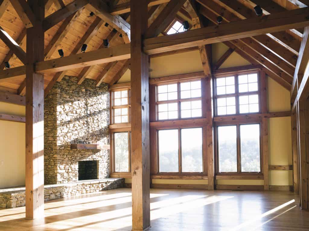 An empty den or living room with a fireplace and wooden beams.