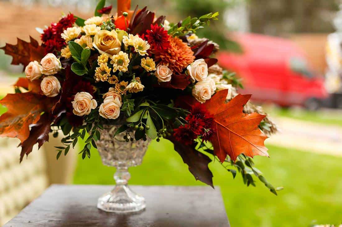 Autumnal flowers and berries in a vase on a table