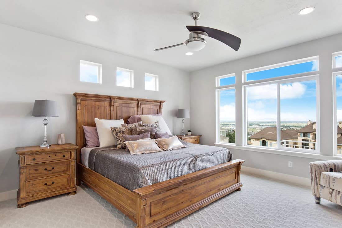 Awning windows above bed with unique ceiling fan and bright walls
