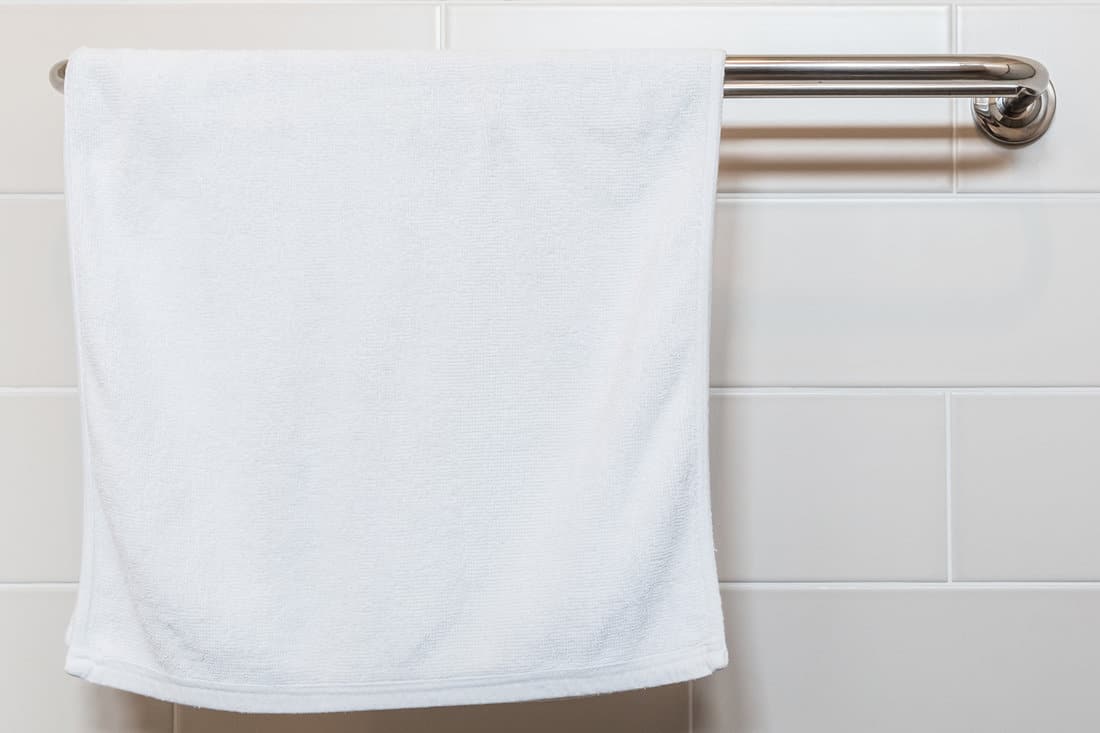 Bathroom Towel - white towel on a hanger prepared to use 