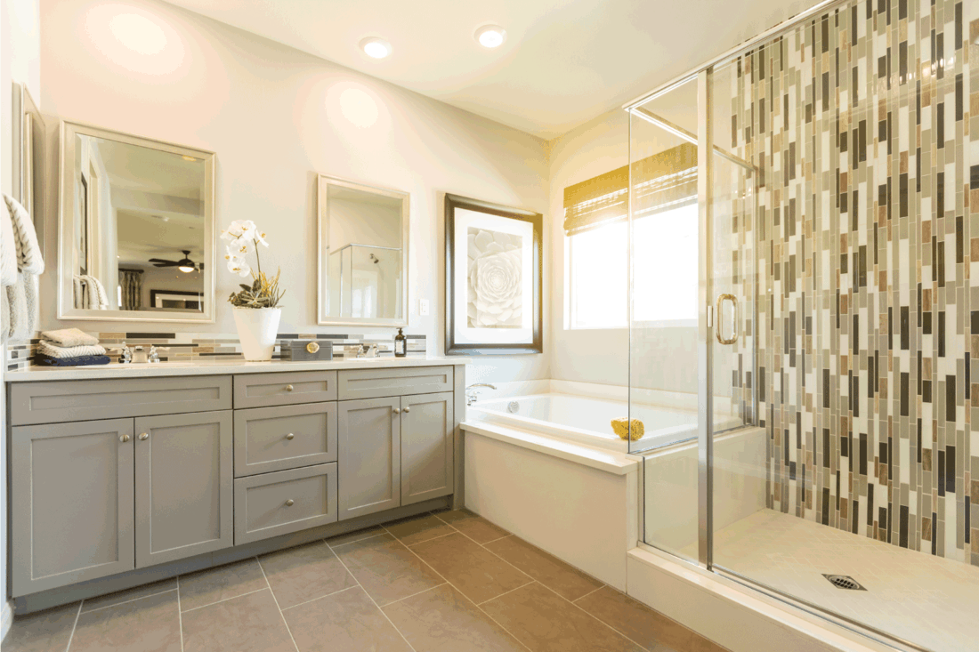 Beautiful Custom Master Bathroom with gray cabinets, large bathtub, walk in shower