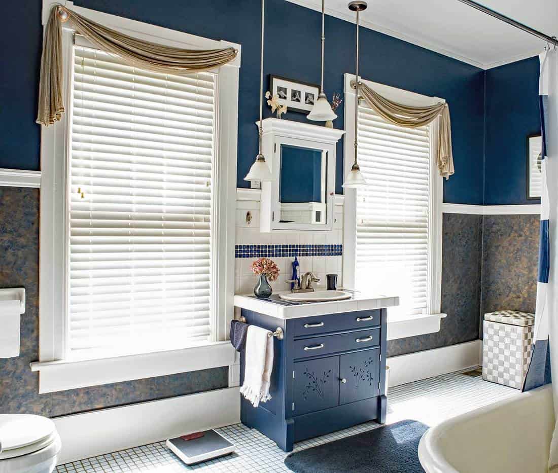 Blue and white bathroom with two large windows
