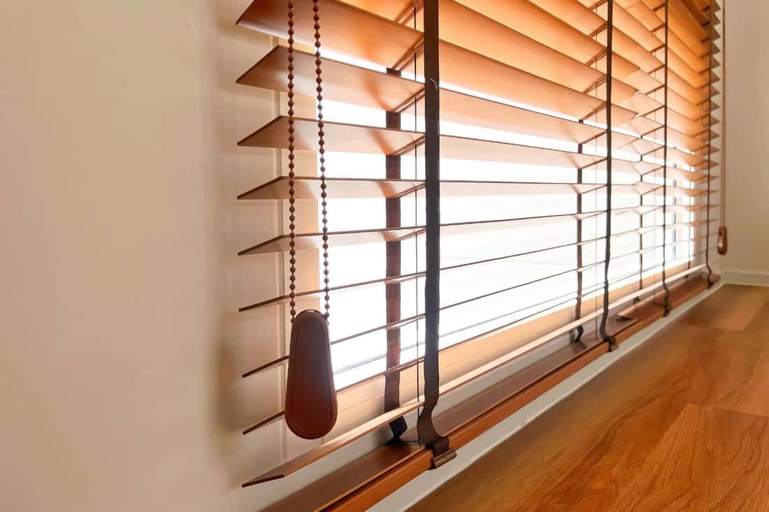 Brown wooden blinds decorate in house on window.