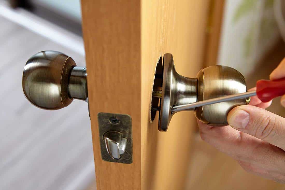 Carpenter fixes door knob with lock and latch on new door