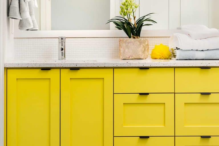 Close up of sink, faucet, countertop, yellow cabinets and mirror, How Long Does It Take To Paint Bathroom Cabinets?