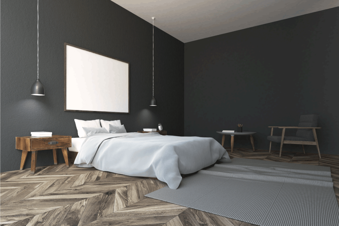 Corner of a modern gray bedroom interior with rug at the end of the bed