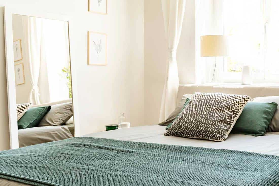 Eco cotton linen and blanket on a bed in nature loving bedroom, Where To Put A Mirror In Your Bedroom? [With Tips According To Feng Shui]
