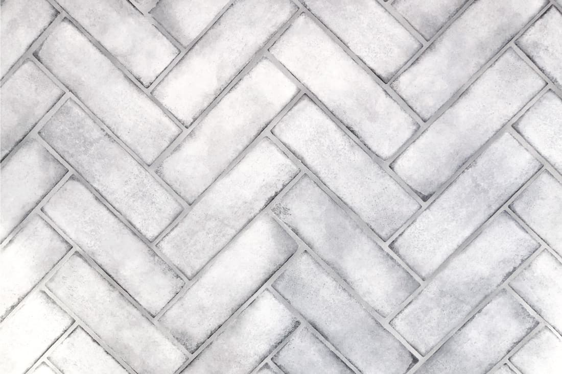 Herringbone tile arrangement on a wall with silver grout