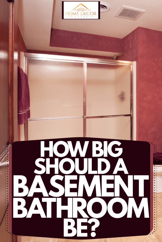 A breathtaking basement with wooden cabinetry and a glass walled bathroom, How Big Should A Basement Bathroom Be?