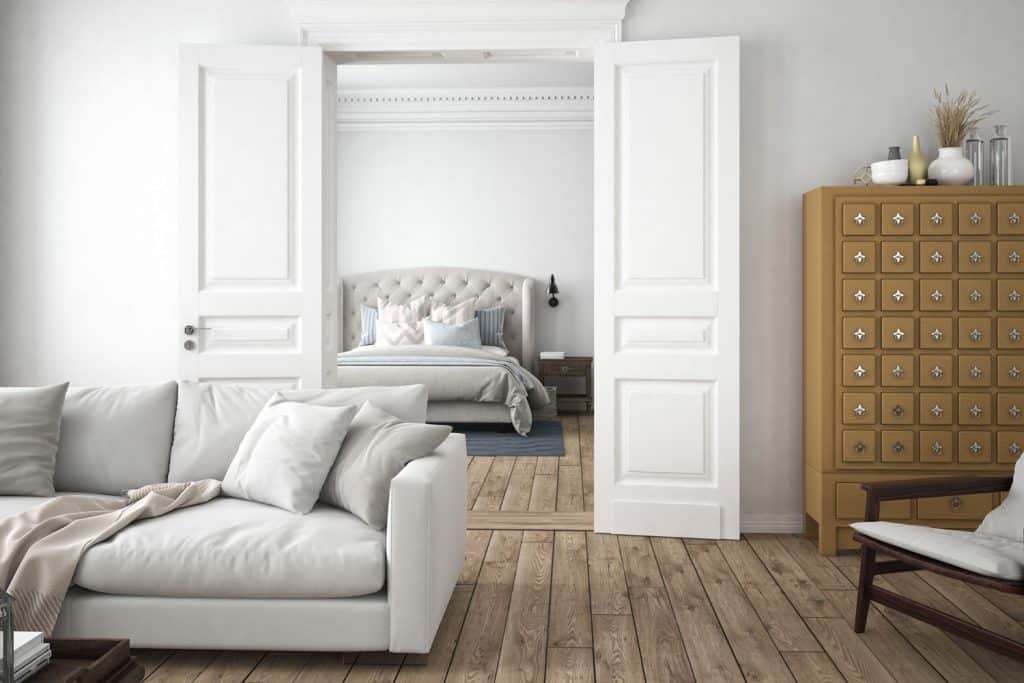 Interior of a homey living room with a white painted French door to the bedroom