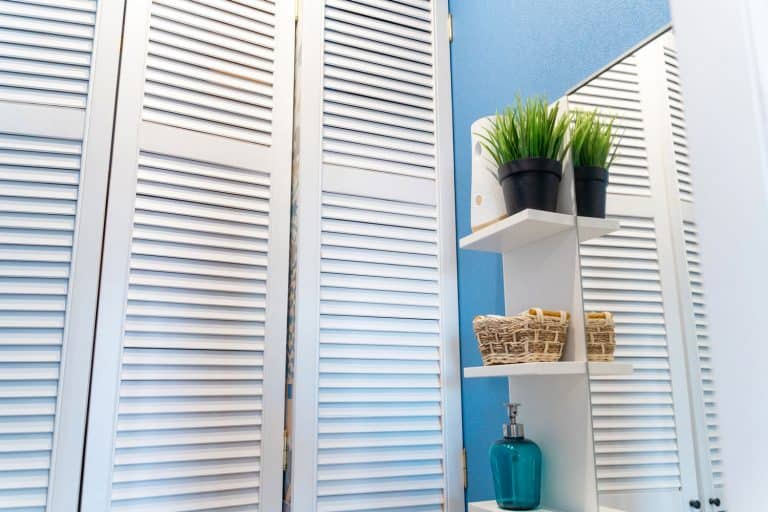 Louvered doors in the closet in the toilet, blue walls and a mirror . How To Install A Louvered Door In 6 Easy Steps