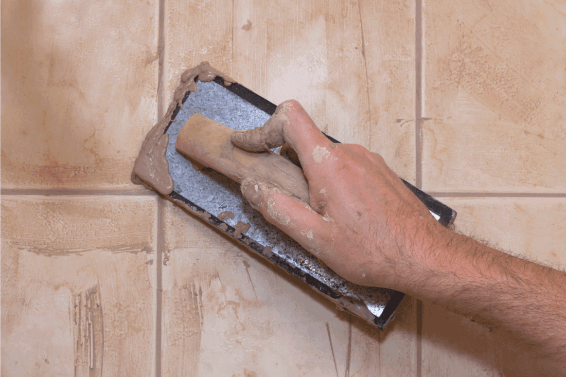 Man's hand with trowel while grouting ceramic tile