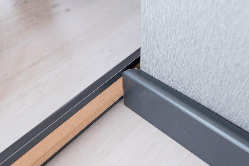 Measuring an angled cut on a white baseboard