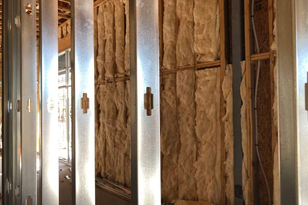 Metal studs inside a living room with visible wooden insulation on the background