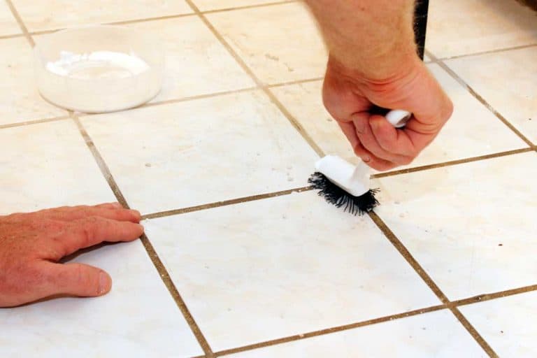 Person cleaning grout with brush, How To Clean Black Grout In A Bathroom