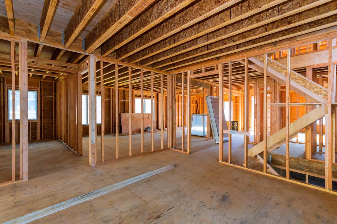 Photo of a house under construction with visible wood framing of the wall and ceiling, How To Attach Wood Framing To Concrete [4 Steps To Follow]