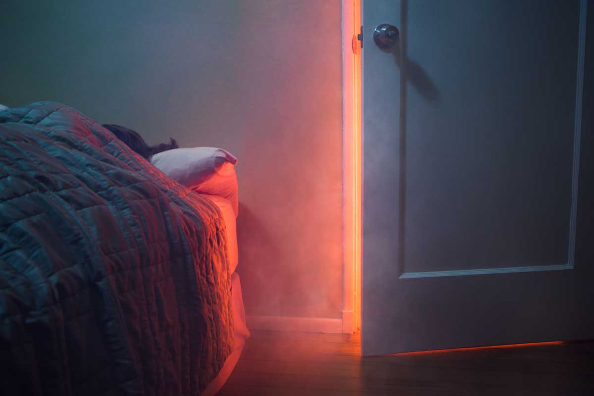 Smoke and light is visible through a slightly open bedroom door, Should You Close Bedroom Doors At Night? [And Should You Lock Them?]