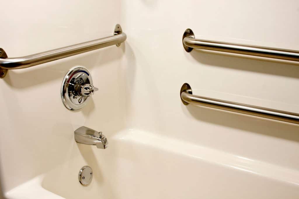 Stainless steel grab bars mounted on the sides of the wall next to the bathtub